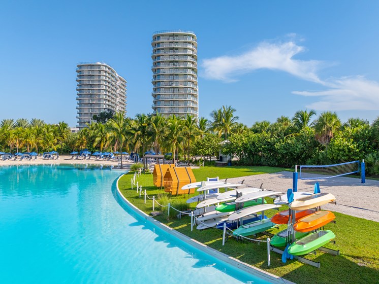 A pool with a row of sun loungers and a row of buildings in the background.